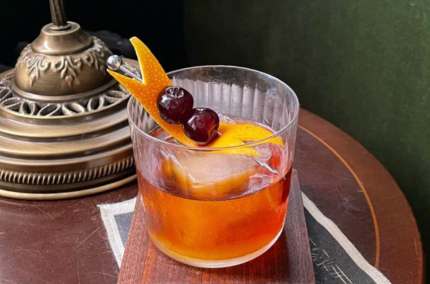 A cocktail in a tumbler on a wooden desk