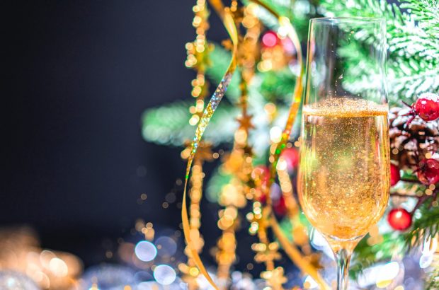 A glass of sparkling wine in front of a Christmas tree