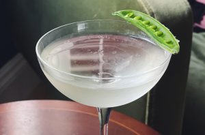 Martini cocktail glass with a pea pod