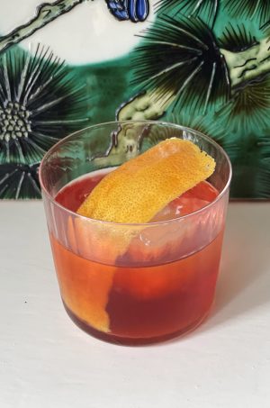 cocktail in a glass with an orange peel garnish