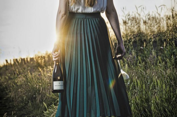 Woman walking through field holding bottle of Philipponnat, Royale Réserve Brut non-vintage Champagne