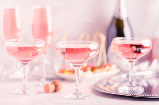 Glasses of pink sparkling wine and bottle on table