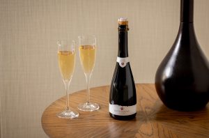 A bottle of Rathfinny Wine Estate's Mini Cuvée 2020, the UKs first 50cl sparkling wine, on a table with two glasses