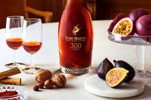 Figs and nuts on a white tablecloth with a bottle of Rémy Martin 300th Anniversary Coupe