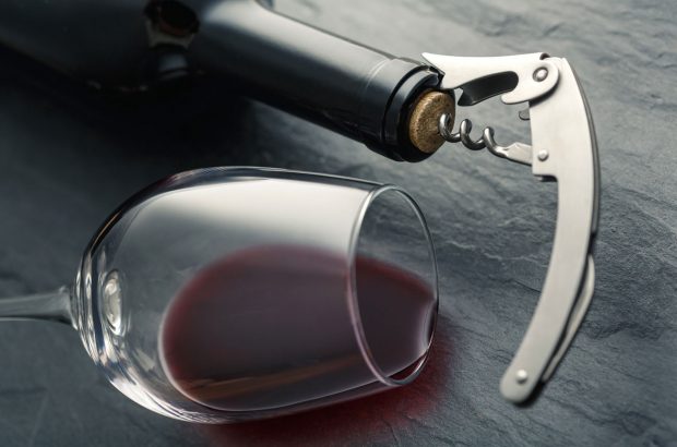 Bottle of wine with cork and glass of red lying on its side