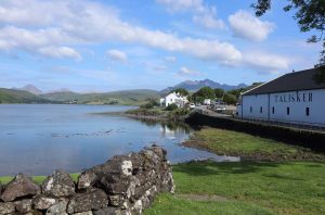 Tailsker whisky distillery on the Isle of Skye by the sea with mountains in the background