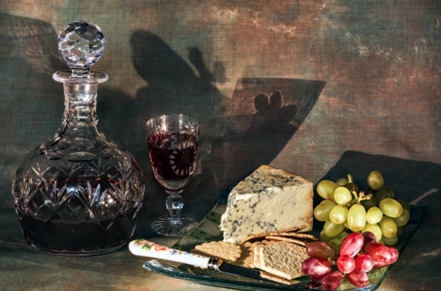 A crystal bottle with Port alongside a selection of cheeses, crackers and grapes