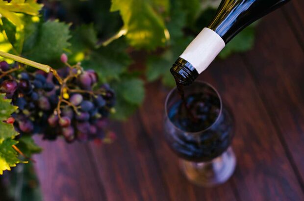 Pouring a glass of wine with grapes in background