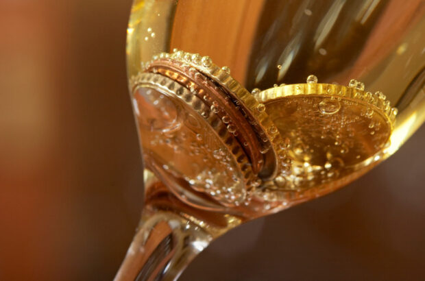 Coins in a glass of sparkling wine
