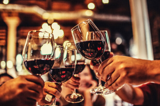 hands raising glasses of wine in cheers motion