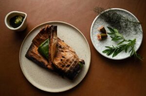 Kiln chef, Beau Clugston's, signature Australian bush-inspired dish – leeks cooked in paperbark, dabbed with native finger lime