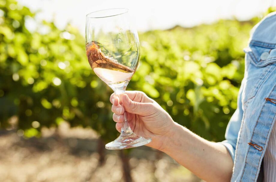 Woman swirling glass of rosé in vineyard