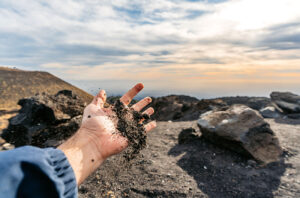 A hand holds volcanic soil Mount Etna Sicily