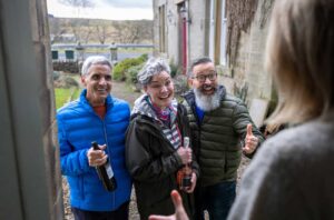 People arriving at a friend's house, on doorstep with bottles of wine