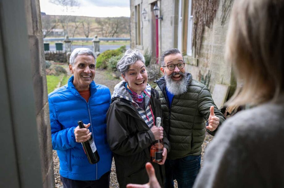 People arriving at a friend's house, on doorstep with bottles of wine