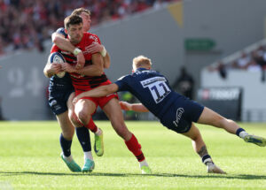 Toulouse's Blair Kinghorn evades a tackle from Sale Sharks’ Tom Roebuck and Arron Reed in the 2025 Champions Cup round-of-16 encounter