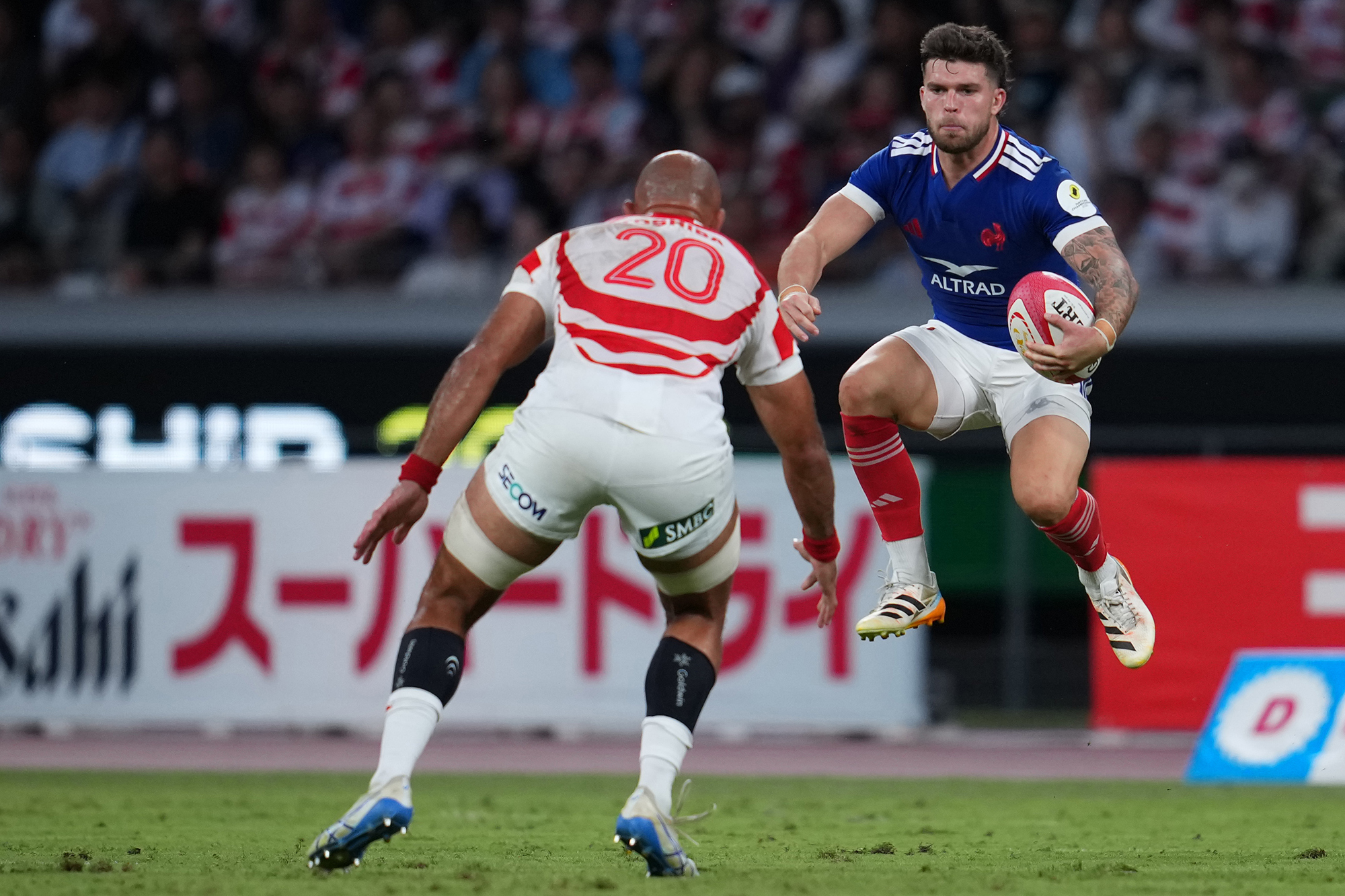 Matthieu Jalibert of France runs with the ball as Japan's Michael Leitch looks on