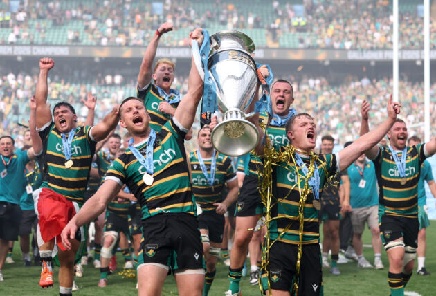 Rory Hutchinson and Fin Smith lift the Gallagher PREM trophy in front of other Northampton Saints players after their 2026 play-off final victory
